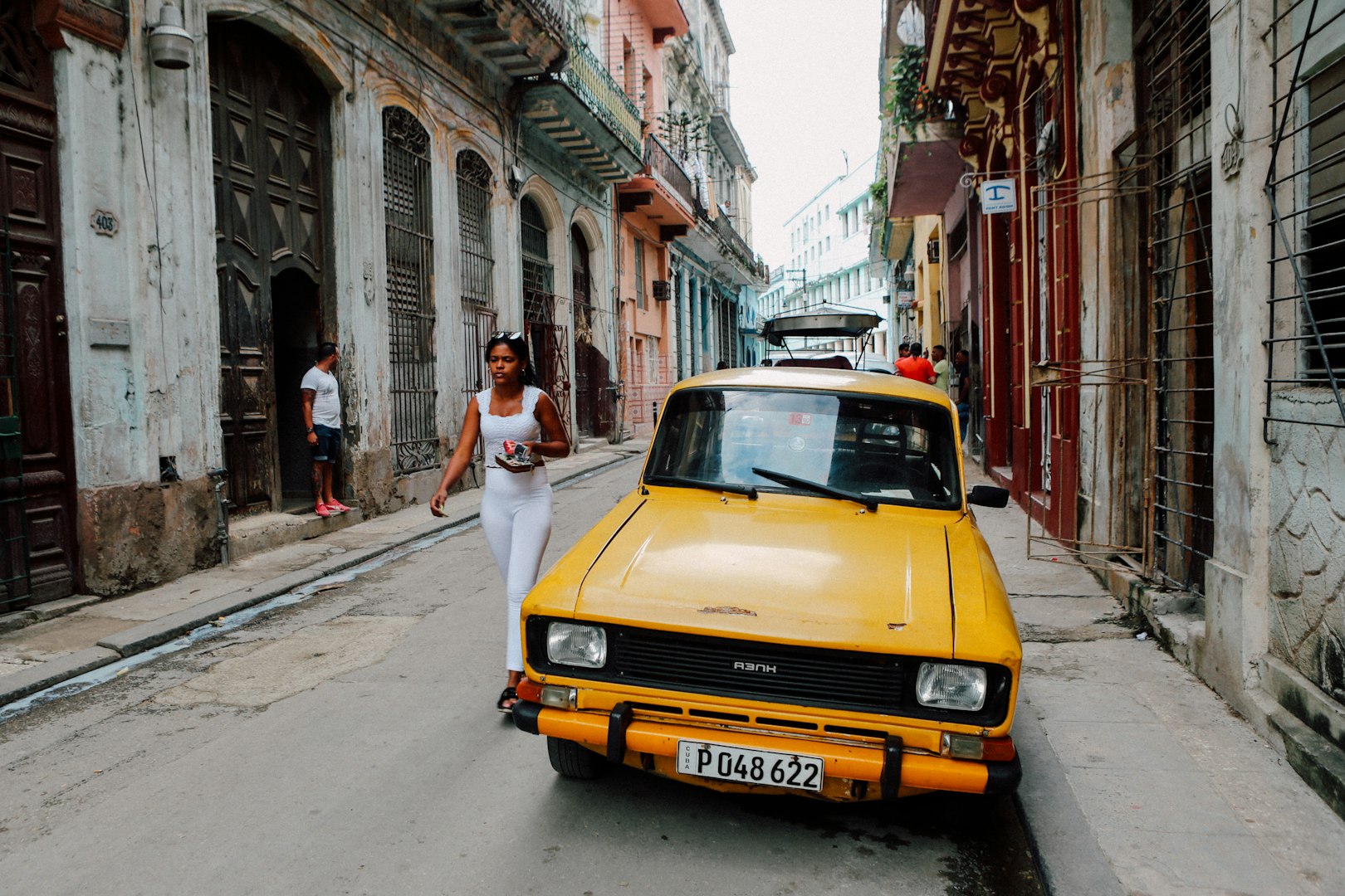 yellow Tofas Murat parked beside white building